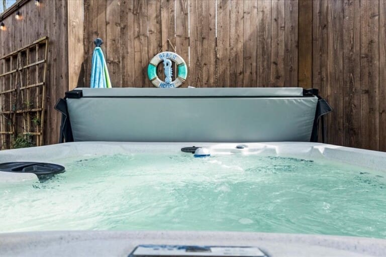 Bubbling outdoor hot tub with life preserver ring on wooden privacy fence at beach vacation rental Texas