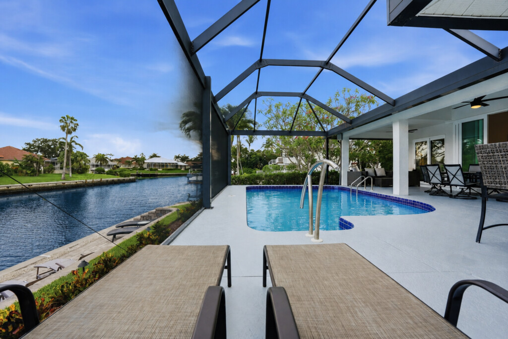 Screened waterfront pool with canal views and relaxing lounge seating at Tigertail Beach Villa, Marco Island FL
