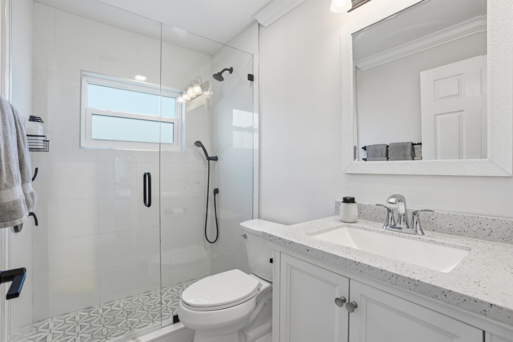 Bright modern bath with glass shower and elegant patterned tile at Tigertail Beach Villa, Marco Island FL
