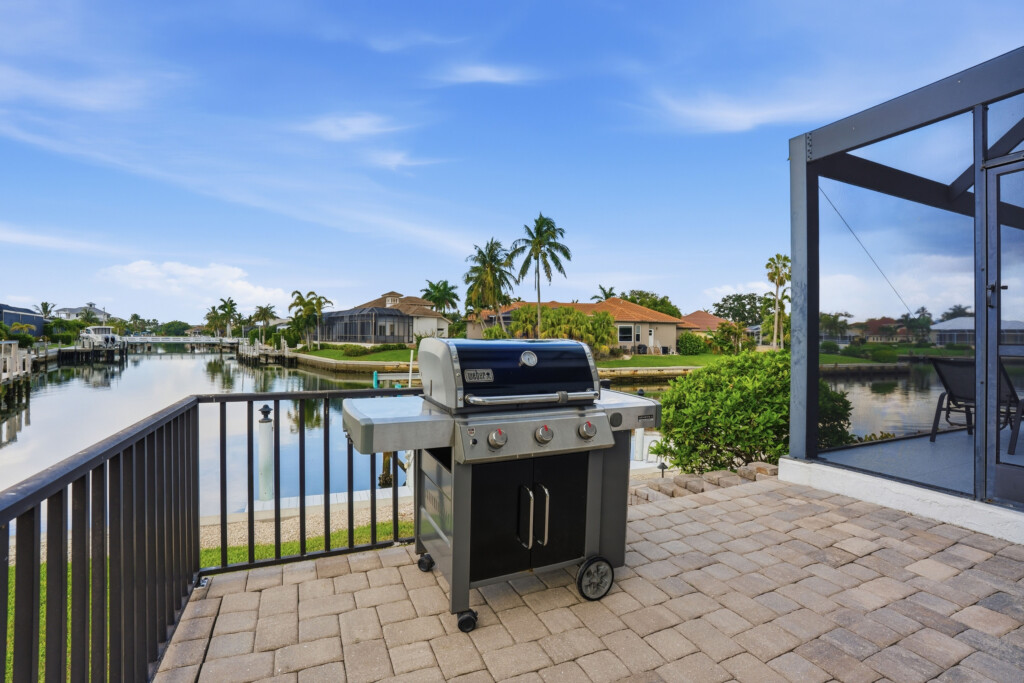 Waterfront patio with grill, screened lanai, and peaceful canal views at Tigertail Beach Villa, Marco Island FL