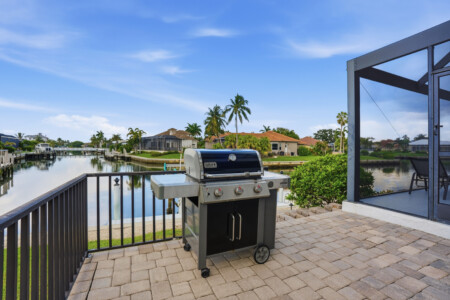 Waterfront patio with grill, screened lanai, and peaceful canal views at Tigertail Beach Villa, Marco Island FL