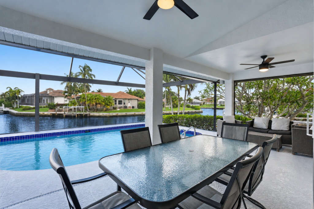 Screened waterfront lanai with pool, dining area, and relaxing canal views at Tigertail Beach Villa, Marco Island FL