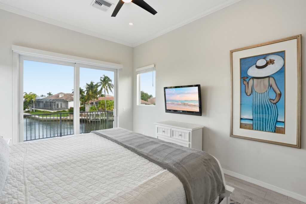 Bright waterfront bedroom with palm views, TV, and relaxing coastal style at Tigertail Beach Villa, Marco Island FL