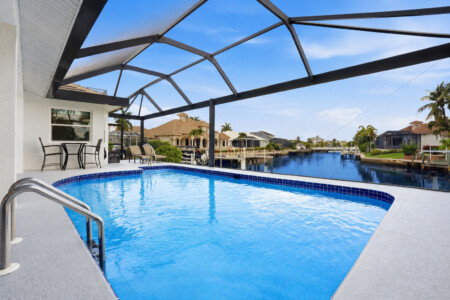 Screened waterfront pool with serene canal views and sunny patio seating at Tigertail Beach Villa, Marco Island FL