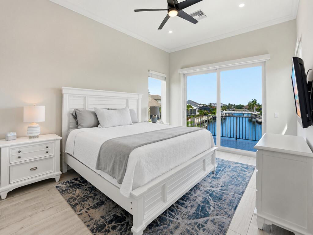Bright waterfront bedroom with private balcony views and airy vaulted ceilings at Tigertail Beach Villa, Marco Island FL