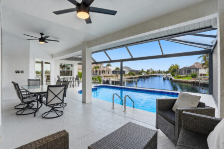 Screened waterfront pool lanai with shaded dining and lounge seating at Tigertail Beach Villa, Marco Island FL