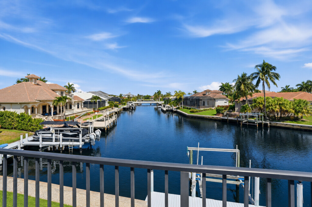 Scenic balcony view overlooking a palm-lined canal with private docks at Tigertail Beach Villa, Marco Island FL