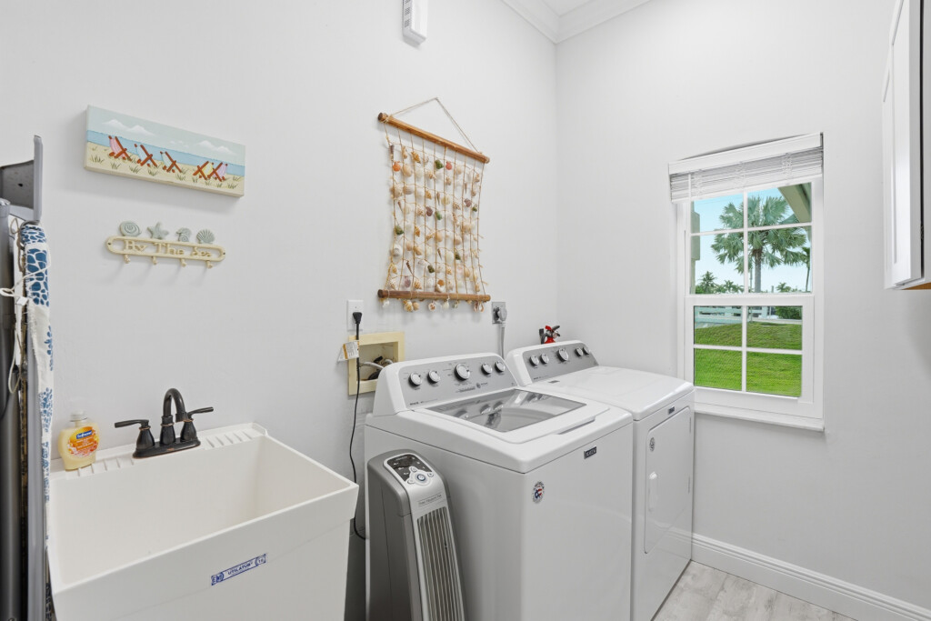 Bright coastal-style laundry room with washer, dryer, and palm views at Tigertail Beach Villa, Marco Island FL