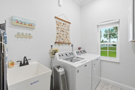 Bright coastal-style laundry room with washer, dryer, and palm views at Tigertail Beach Villa, Marco Island FL