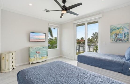 Bright coastal twin bedroom with balcony access and palm-view natural light at Tigertail Beach Villa, Marco Island FL