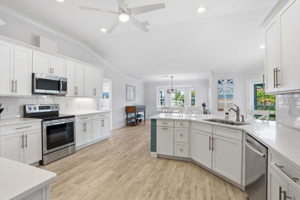 Bright open kitchen with large island, stainless appliances, and airy dining space at Tigertail Beach Villa, Marco Island FL