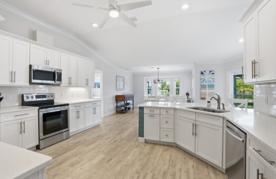 Bright open kitchen with large island, stainless appliances, and airy dining space at Tigertail Beach Villa, Marco Island FL